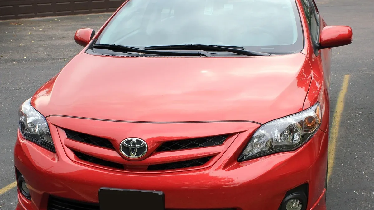 The front of a red Toyota Corolla parked in a parking lot.